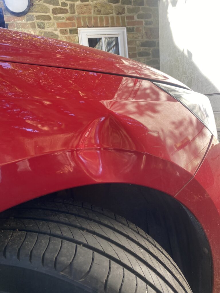 Before wing dent repaired with paintless dent removal